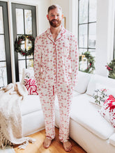 This festive unisex pajama set features a cheerful Santa Claus print scattered across a soft white background with bright red accents along the buttons, piping, and drawstring. The playful all-over St. Nick brings a touch of nostalgia and fun to your holiday sleepwear collection. Made from cozy, breathable fabric, these unisex Christmas pajamas are perfect for lounging, family photos, or Christmas morning gift opening.
